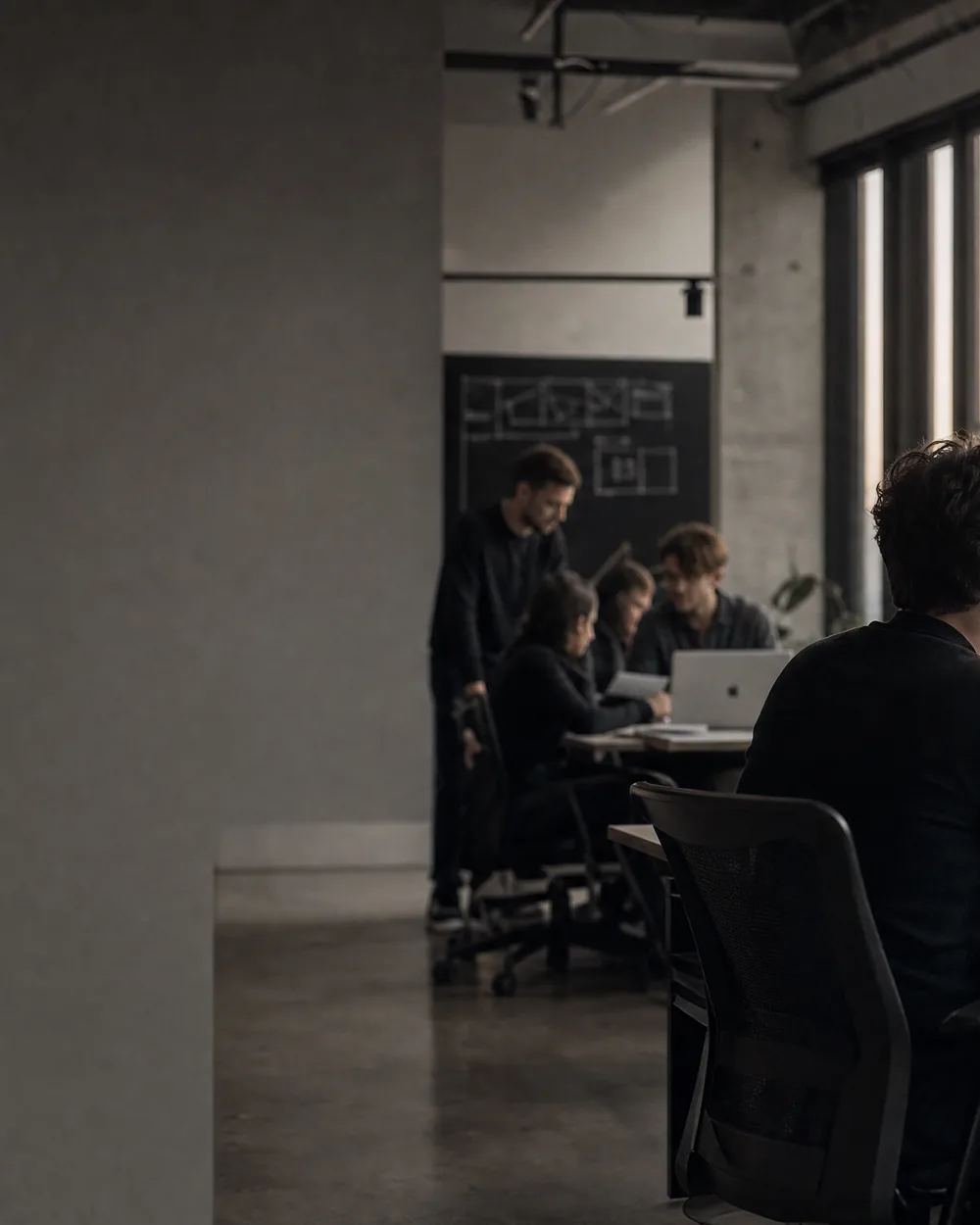 A dark studio of people working at lit screens.