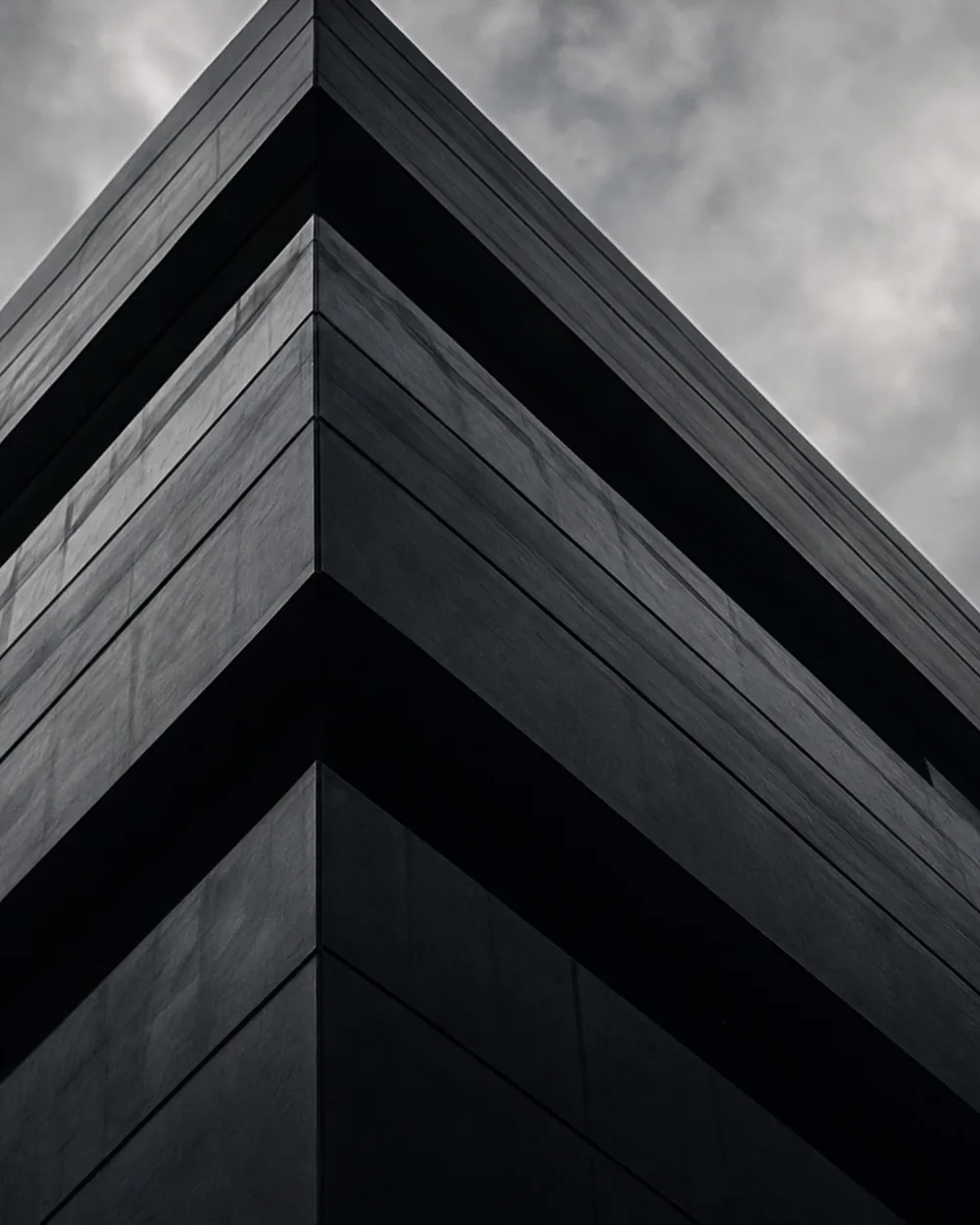 A concrete building of hard angles with a single figure at its base.
